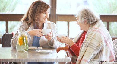 caregiver and senior woman having a cup of tea while having a conversation