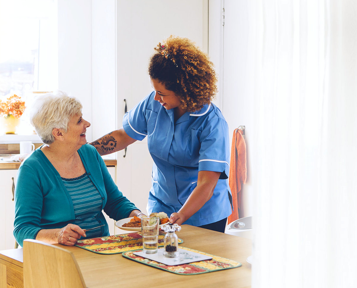 caregiver serving the meal to the senior woman
